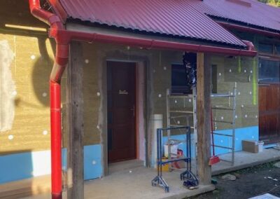 Zateplenie rodinného domu v Chlebniciach s červenou strechou a lešením